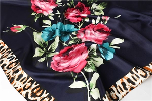 Macro detail of silk-satin scarf featuring red rose floral pattern and leopard print border