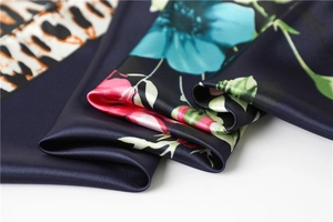 Macro detail of glossy leopard print and floral silk satin scarf with elegant folds