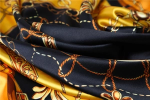 Detailed close-up of glossy satin fabric with elegant gold chain patterns on black background