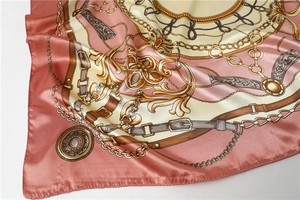 Detailed macro view of satin scarf showing gold chain patterns and pink baroque textures