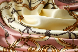 Detailed close-up of pink and cream satin scarf with chain and rope luxury patterns