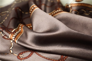 Macro shot of satin scarf featuring intricate golden chain patterns and smooth texture