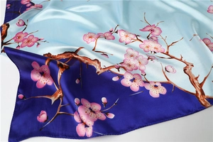 Close-up of silk square scarf featuring plum blossom print and blue gradient colors
