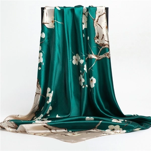 Detail of silk satin scarf featuring elegant white plum blossom prints on dark green fabric
