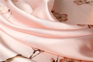 Close-up of pink silk scarf showing smooth texture and elegant plum blossom patterns