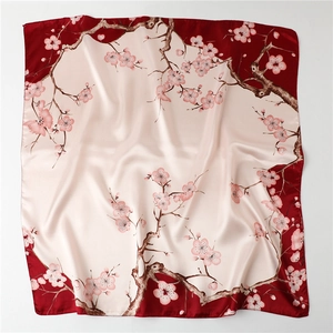 Detailed view of plum blossom pattern on red and cream silk square scarf with soft folds