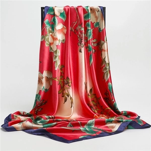 Red silk scarf with floral camellia print and blue borders hanging on a stand