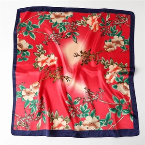 Detailed flat lay of red floral silk scarf with navy borders and elegant petal patterns