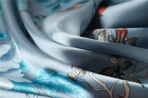 Macro shot of satin silk scarf showing blue floral patterns and smooth draped texture