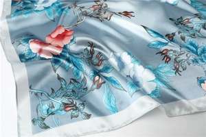 Detailed close-up of grey-blue silk scarf with delicate floral prints and satin texture