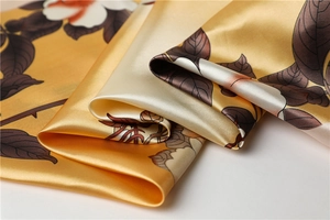 Detailed close-up of glossy floral satin silk scarf with elegant yellow gradient texture