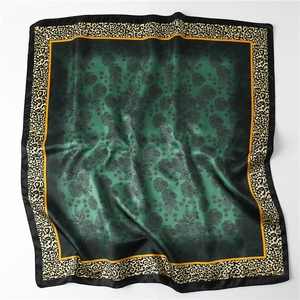 Dark green silk scarf with leopard print and floral patterns on a grey background