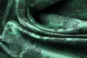 Macro shot of dark green satin scarf with elegant black floral patterns and silky texture