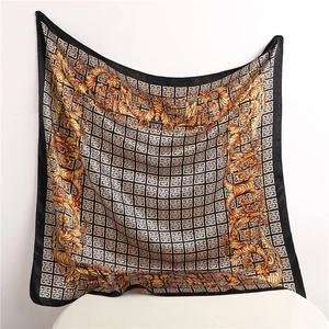 Elegant black and gold square silk scarf with baroque patterns on white chair