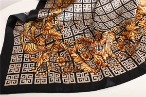 Detailed close-up of dark green silk scarf with baroque floral patterns and smooth texture