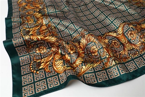 Detailed macro view of dark green silk scarf with golden baroque floral patterns