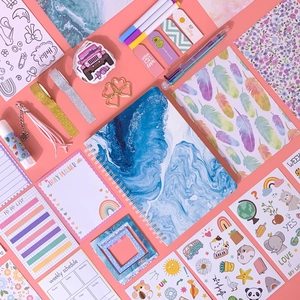 Flat lay of pink DIY journal set with marble notebook, stickers, and planning accessories