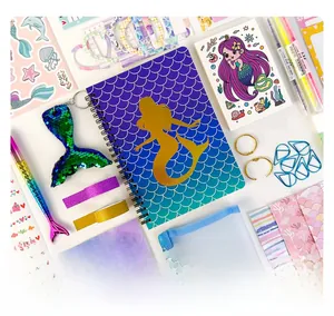 Flat lay of mermaid themed DIY journal gift set with notebook, sequin pen and stickers