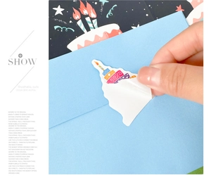 Close-up of vibrant birthday cake stickers with a hand peeling them for DIY cards