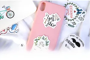 Close-up of wedding themed stickers on a pink phone case and white laptop lid