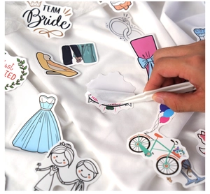 Tweezers peeling a heart sticker from a 50pcs wedding cartoon set on silk background