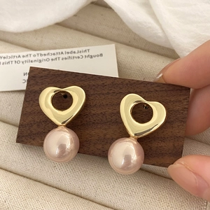 Gros plan de boucles d'oreilles vintage en forme de cœur doré avec perles roses