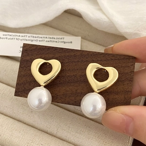 Gros plan détaillé de boucles d'oreilles vintage cœur avec de grandes perles blanches