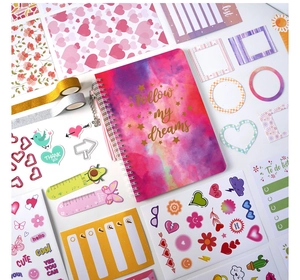 Flat lay of pink DIY journal set with glitter tape, stickers and a spiral notebook