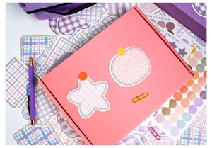 Detail of DIY journal kit featuring pink box, purple gel pen, and grid pattern stickers