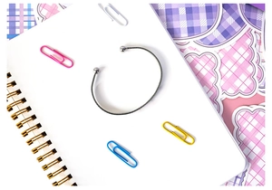 Minimalist silver-tone open cuff bracelet with spherical ends on a white spiral notebook