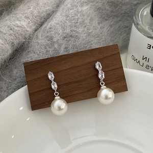 Détail de boucles d'oreilles pendantes en perles avec zircons étincelants de taille marquise