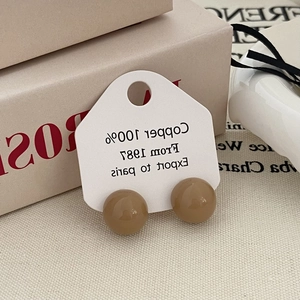 Close-up of khaki spherical stud earrings on white copper material card display