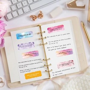Watercolor inspirational stickers with English quotes on a leather journal with keyboard