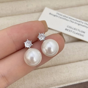 Close-up of elegant white pearl stud earrings with sparkling cubic zirconia in silver