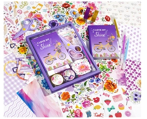 Flat lay of purple DIY journal set with notebook, stickers, scissors and tapes