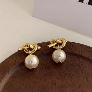 Macro shot of French vintage gold knot earrings with elegant pearl drop detail