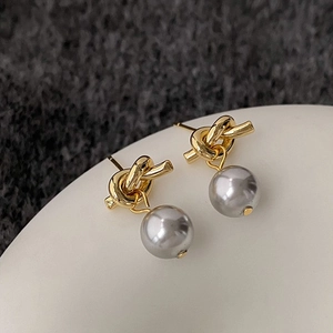 Detail of vintage knotted pearl studs featuring gold metal and grey luster pearls