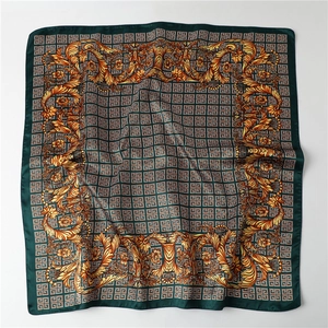 Detail of dark green silk scarf with golden baroque patterns and silky smooth texture