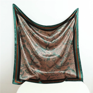 Detail of a large silk-like square scarf featuring a classic emerald and paisley print