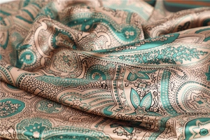Macro shot of 90cm paisley silk scarf showing green floral satin fabric texture