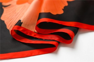 Vue détaillée d'un foulard en soie à fleurs de pivoine orange avec bordure rouge
