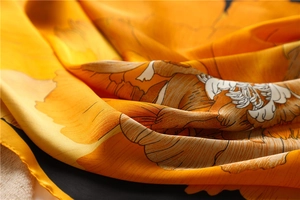 Détail d'un foulard en soie montrant des motifs floraux et une texture luxueuse