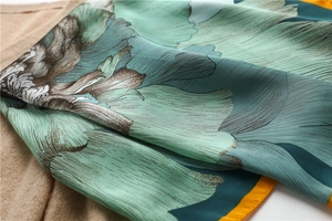 Détail d'un foulard en soie avec motifs floraux, tons vert menthe et bords roulés
