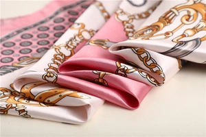 Detailed close-up of a satin square scarf with gold chain and equestrian motif pattern