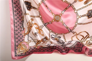 Detail of pink and white silk-like satin scarf with golden equestrian chain pattern