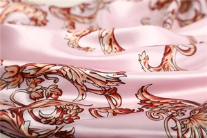 Close-up of pink silk square scarf with baroque pattern showing smooth texture and sheen
