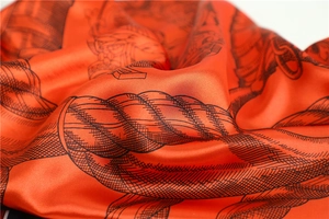 Detail of red satin scarf showing silky texture and vintage knot patterns with soft folds