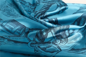 Detailed close-up of peacock blue silk scarf with nautical rope patterns and glossy texture