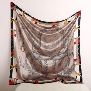 Detailed view of large satin silk scarf featuring classic equestrian buckle and belt patterns