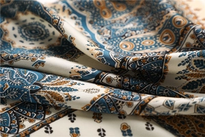 Macro shot of silk satin scarf featuring intricate paisley and mandala patterns in navy and gold
